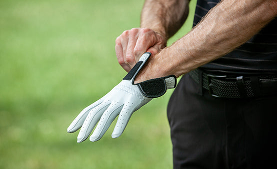 a golfer putting on his golf glove